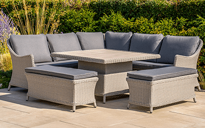 a rattan corner sofa set with adjustable table with a hedge background