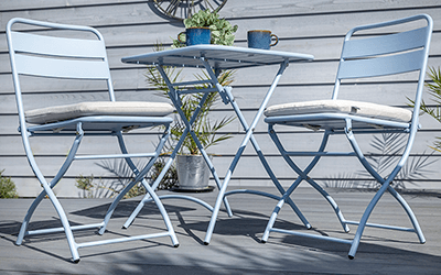 Hartman Urban Folding Bistro Set on a patio with a house with French doors in the background.